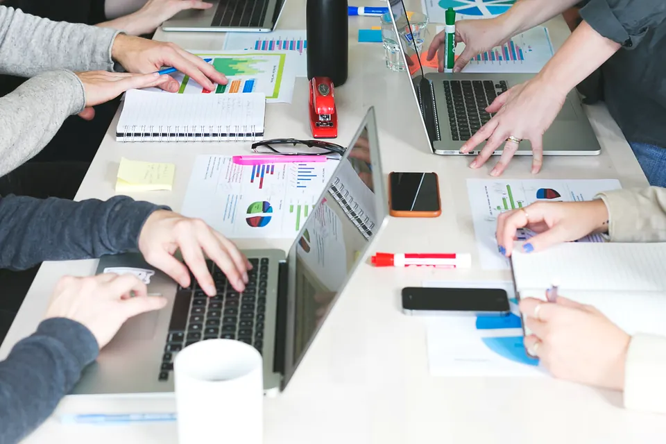 A team working through charts and laptops at a shared desk