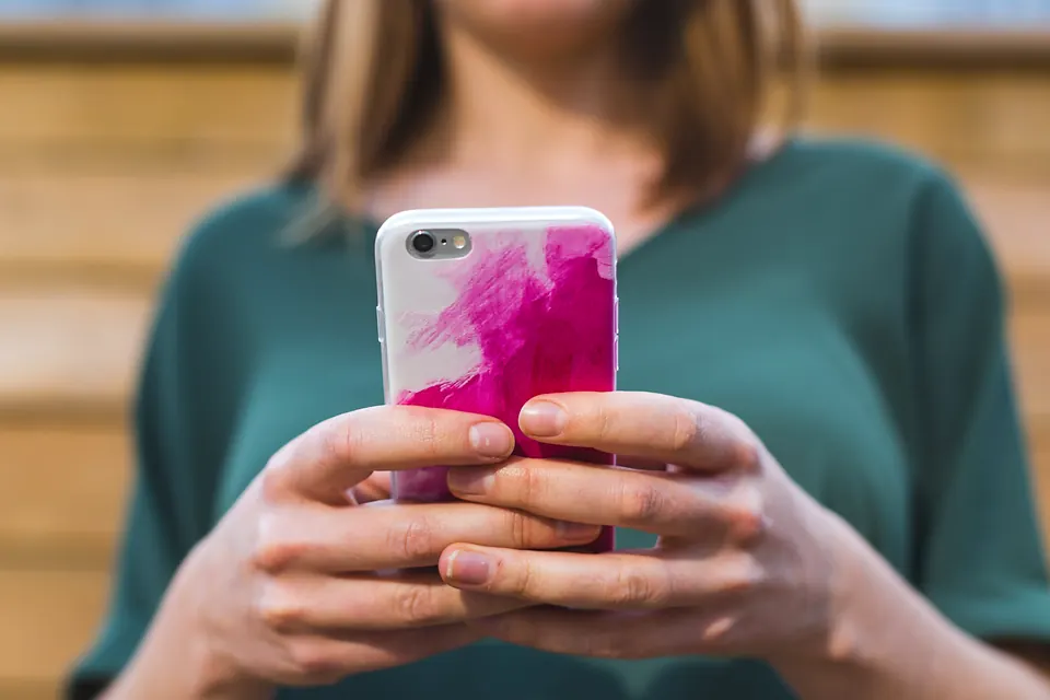 Hands holding a phone with a pink patterned case