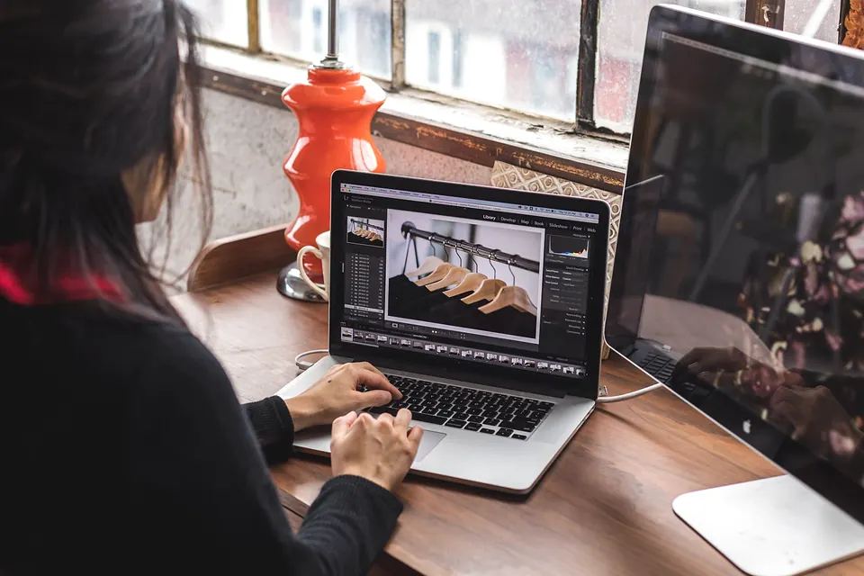 A woman editing photos on a laptop in a bright loft studio